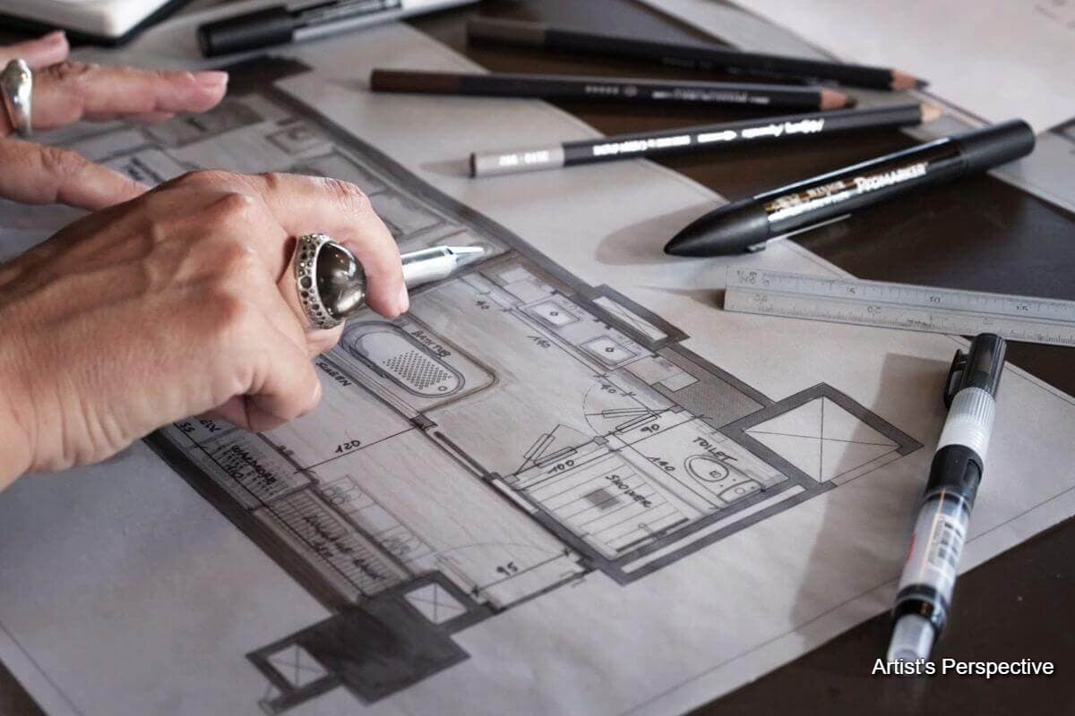 Close-up of an architect reviewing a residential floor plan with drafting tools and pencils on a worktable
