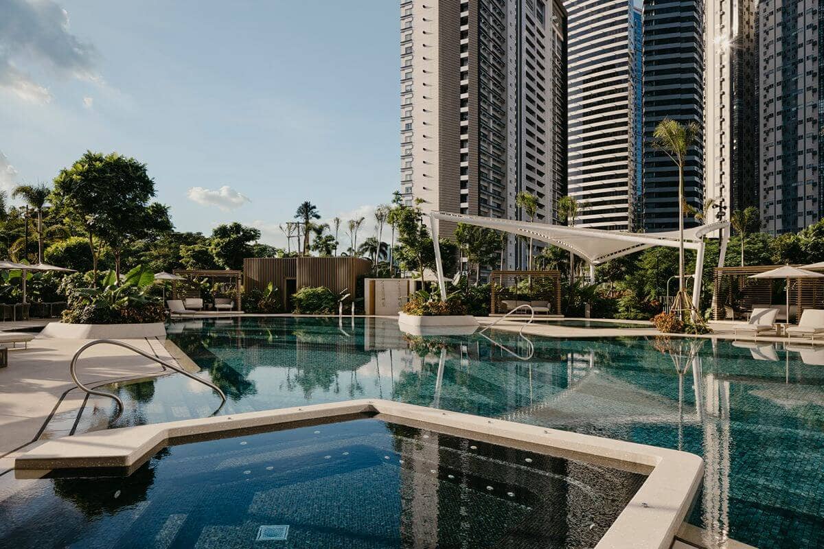 Modern condominium towers surrounding a landscaped pool and green amenity spaces designed for sustainable luxury living