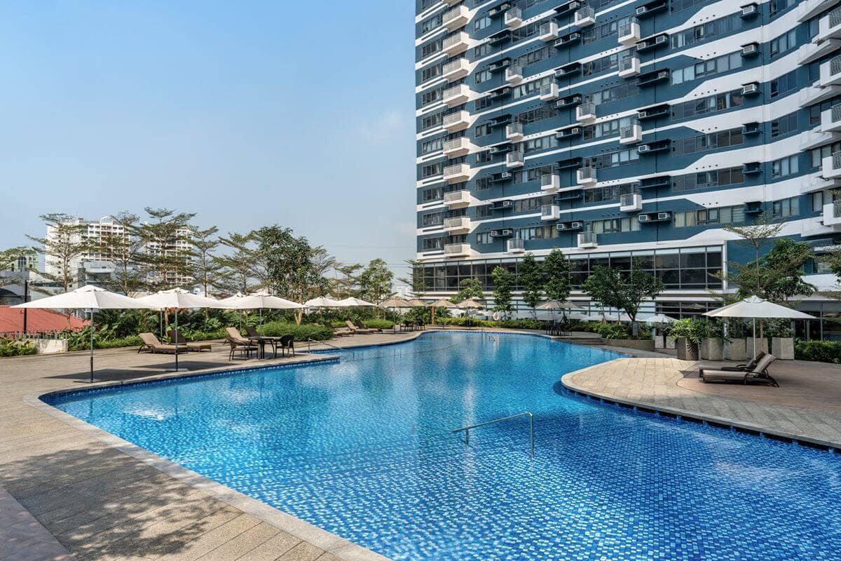 Well-maintained condominium swimming pool surrounded by lounge areas and residential buildings, reflecting professional property management