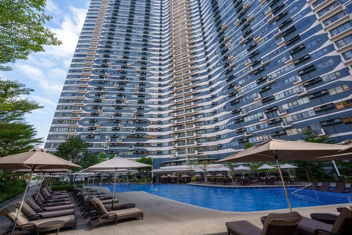 Luxury condominium towers surrounding a resort-style swimming pool, highlighting premium urban living and investment appeal